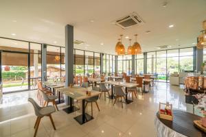 a restaurant with tables and chairs and windows at The Tree Riverside Resort Kaeng Krachan in Kaeng Krachan