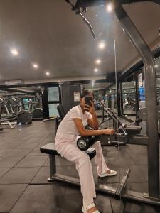 a man sitting on a bench in a gym talking on a cell phone at Ronika devi in Savu