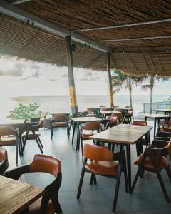 a restaurant with tables and chairs and the ocean at The Angkal Resort in Nusa Penida