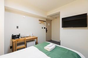 a bedroom with a bed and a desk and a television at アメ村ガーデンホテルAmemura Garden Hotel in Osaka