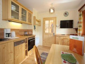 a kitchen with wooden cabinets and a table and a television at Peaceful Cottage near Ski Area in Gmünd in Gmünd in Kärnten