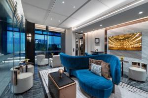 a living room with a blue couch and some windows at La Clef Bangkok by The Crest Collection in Bangkok