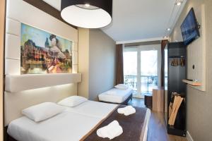 a small room with two beds and a tv at Hotel Mosaic City Centre in Amsterdam