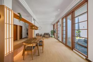 a dining room with a table and chairs and windows at Kuma Villa Bandung in Bandung