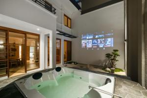 a large bath tub in a bathroom with a tv at Kuma Villa Bandung in Bandung +29 photos