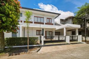 a white house with a tree in front of it at Kuma Villa Bandung in Bandung