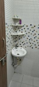a bathroom with a sink in a white tiled wall at Pb Legacy hotel in Noida