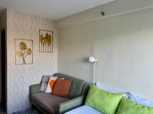a living room with a green couch with colorful pillows at Unit 28 Mountain View Studio by Ems in Dumaguete