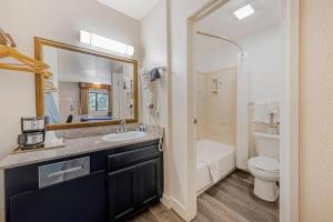 a bathroom with a sink and a toilet and a mirror at Rodeway Inn at Nevada State Capitol in Carson City