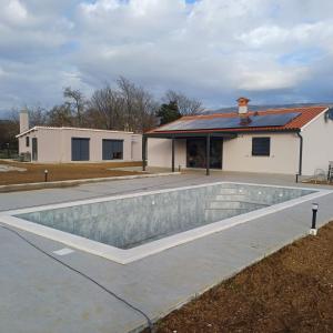 a swimming pool in front of a house at Villa Germini in Polje Čepić