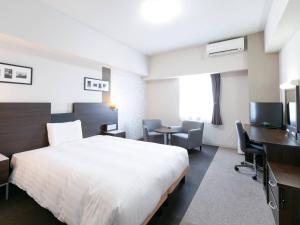 a hotel room with a bed and a desk and a television at Comfort Hotel Central International Airport in Tokoname