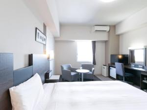 a hotel room with a bed and a table and chairs at Comfort Hotel Central International Airport in Tokoname