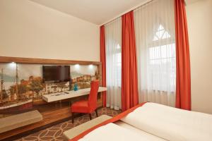 a hotel room with a bed and a desk and a television at H+ Hotel Lübeck in Lübeck