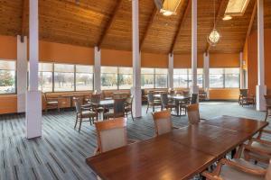 a dining room with tables and chairs and windows at Clarion Pointe Medicine Hat Saamis Tepee in Medicine Hat