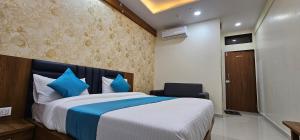 a bedroom with a large bed with blue pillows at Hotel Empire in Vapi