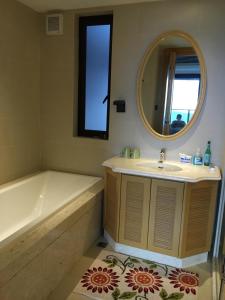 a bathroom with a tub and a sink and a mirror at Marcia's Guest House in Wanning