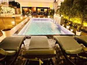 a large swimming pool with chairs and a table at Friends Villa Nainwal in Gurgaon