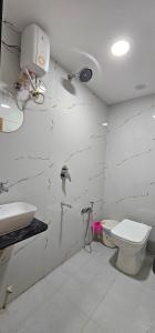 a white bathroom with a toilet and a sink at Hotel Empire in Vapi