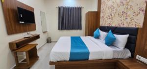 a bedroom with a bed with blue and white sheets at Hotel Empire in Vapi +6 photos