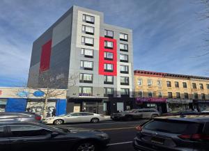 a tall building on a city street with parked cars at Sleep Inn in Brooklyn