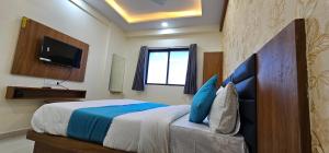 a bedroom with a bed with a tv on the wall at Hotel Empire in Vapi
