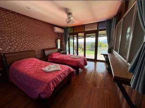 a bedroom with two beds with red sheets and windows at Wanwan Lanna By Pat in Ban Huai Thong