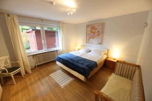 a bedroom with a bed and a chair and two windows at Ferienwohnung Am Hohen Berge in Lauenburg