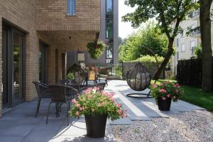 a patio with chairs and tables and flowers at Lapwing Residence Sopot in Sopot