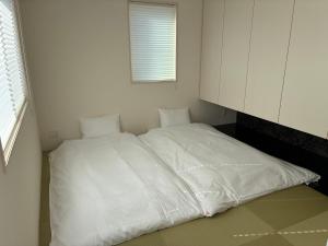 a white bed in a room with a window at Aoshima Seaside Village in Miyazaki