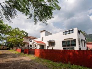 ein weißes Haus mit einem roten Zaun davor in der Unterkunft Palette Mountain Mist Villa | 2BHK | Jacuzzi | Pool | Lonavala in Lonavla