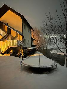a house in the snow with a bench in front of it at Apartman Removic in Ivanjica
