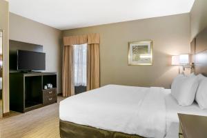 a hotel room with a bed and a flat screen tv at Quality Inn & Suites Monroe in Monroe