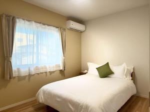 a bedroom with a white bed with a window at Akikawa Waifu 2 プレミアム木造 一棟貸切ヴィラ in Kikuchi