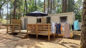 a tiny house with an umbrella and clothes hanging up at Camping Parc Saint Sauvayre in Vagnas