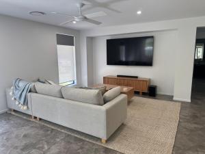 a living room with a couch and a flat screen tv at The Ponds at Mudgeeraba in Gold Coast