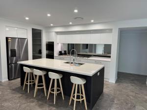 a kitchen with a large island with bar stools at The Ponds at Mudgeeraba in Gold Coast