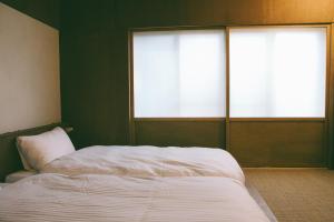 a bedroom with a white bed and two windows at ONYO Hotel and Lounge in Ueda