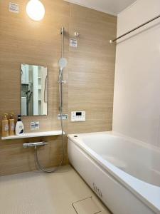 a bathroom with a bath tub and a mirror at Akikawa Koshi 12 プレミアム木造 一棟貸切ヴィラ in Yuge +11 photos