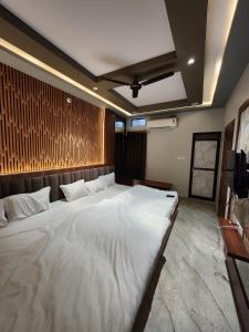 a large white bed in a room with a tv at Hotel Shree Sanwaliya in Ujjain