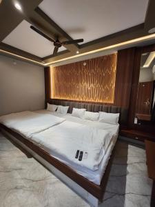 a bedroom with a large bed with white sheets at Hotel Shree Sanwaliya in Ujjain