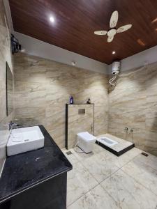 a bathroom with a sink and a toilet and a ceiling fan at Hotel Shree Sanwaliya in Ujjain +16 photos