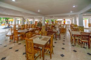 an empty restaurant with wooden tables and chairs at Grand Melka Hotel in Lovina