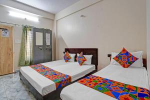 a bedroom with two beds with colorful sheets at Via Lords inn in Bhopal