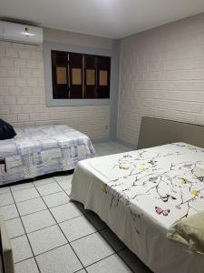 a bedroom with two beds and a window at Casa Familiar Ampla - Conforto e Lazer no Frances in Praia do Frances