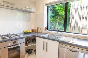 a white kitchen with a sink and a window at Hot Water Hideaway in Hotwater Beach