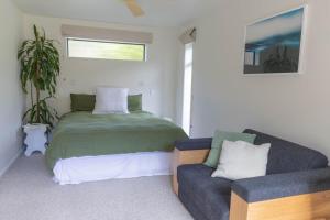 a bedroom with a bed and a couch at Hot Water Hideaway in Hotwater Beach