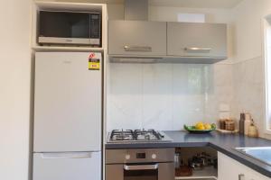 a kitchen with a refrigerator and a stove and a microwave at Hot Water Hideaway in Hotwater Beach +16 photos