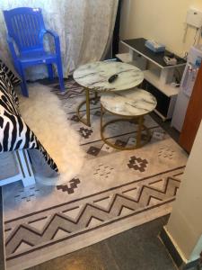 a room with a table and two stools on a rug at Hornville suites in Ongata Rongai 