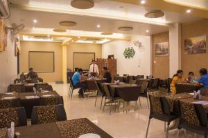 a restaurant with people sitting at tables in a room at Hotel Gulmohar Pride in Ahmadnagar