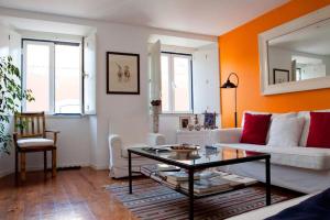 リスボンにあるDuplex do Pipasの白いソファとオレンジ色の壁が備わるリビングルーム